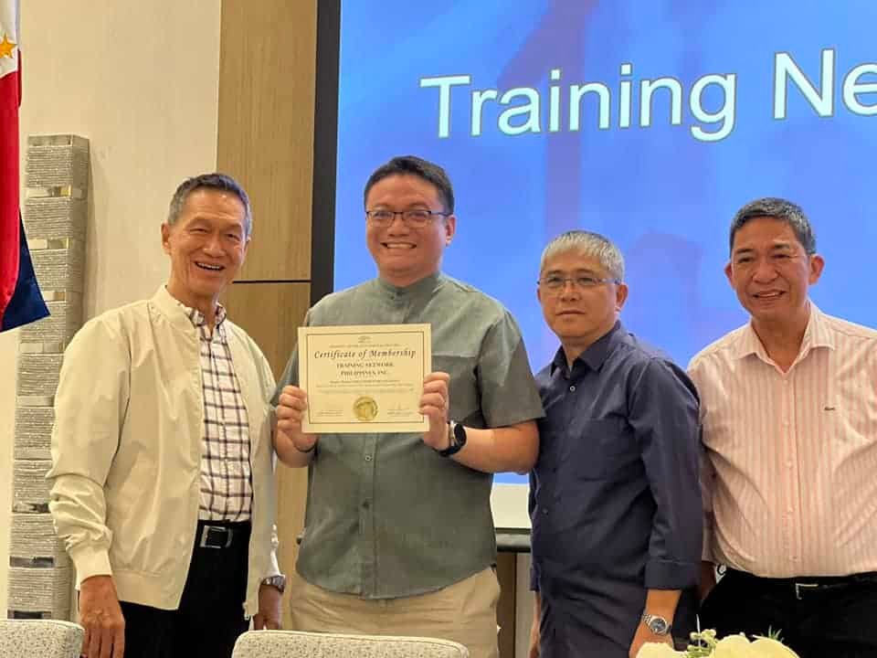 Four men standing in front of a screen holding a certificate.