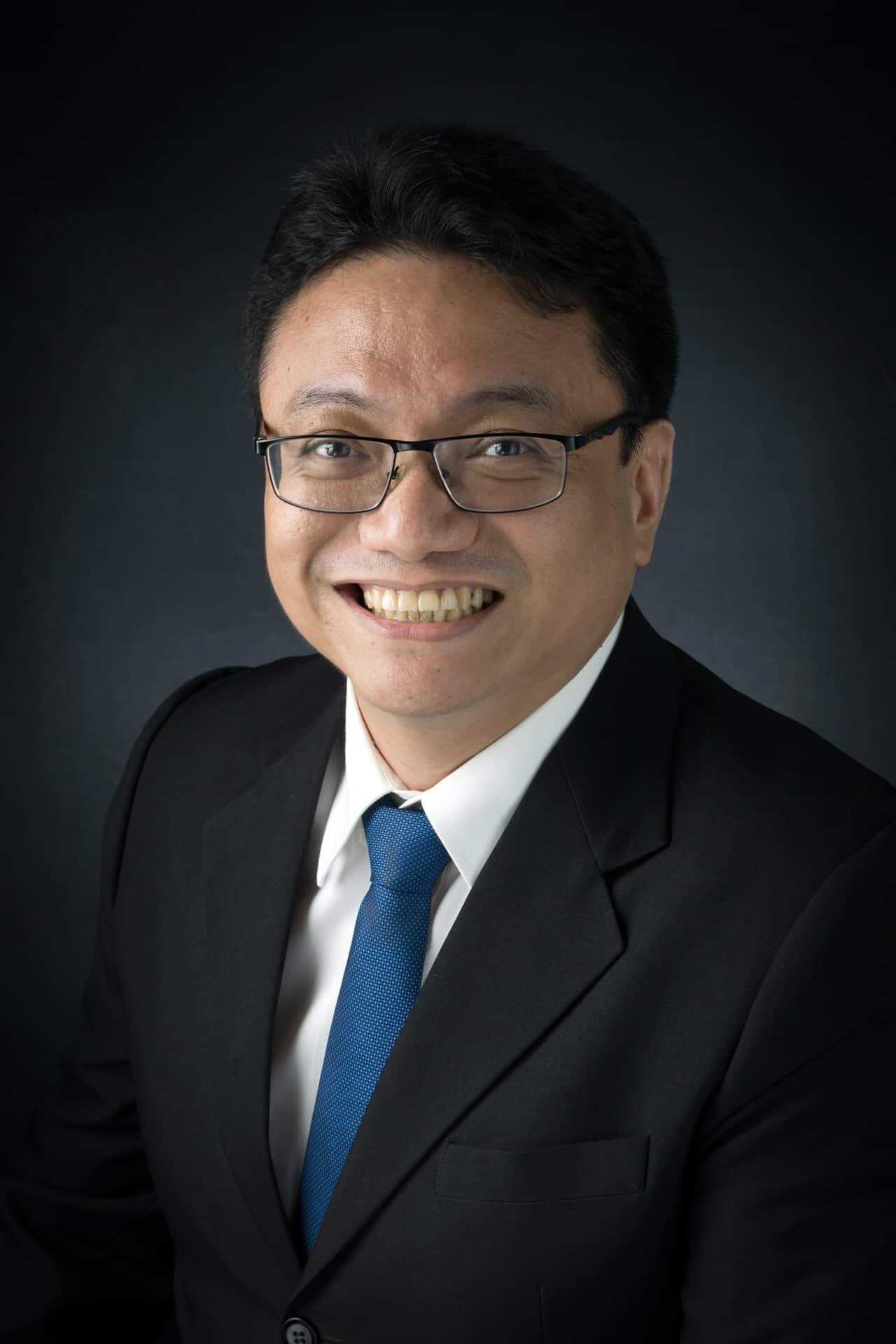 A man in a suit and tie smiling for the camera.