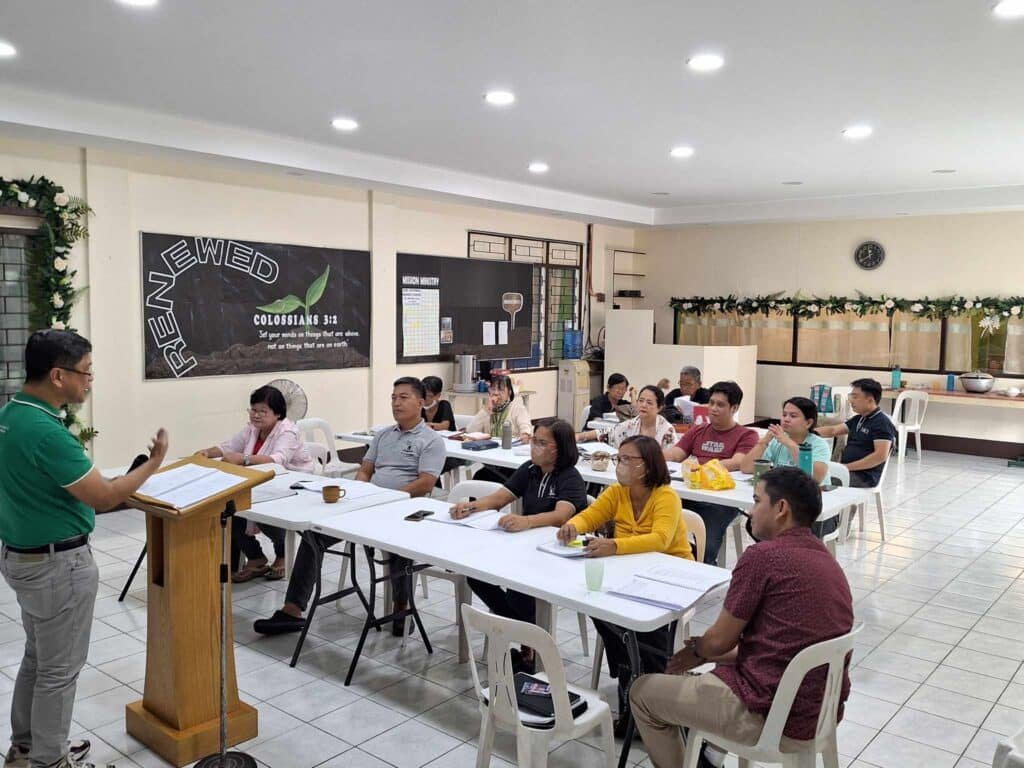 A group of people sitting at tables in a classroom.