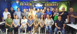 A group of people posing in front of a jesus christ sign.